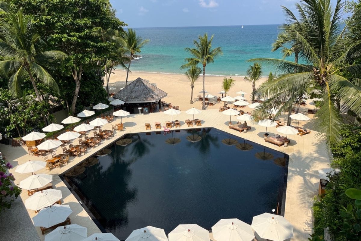 Beachfront cottages and palm trees at The Surin Phuket overlooking the Andaman Sea